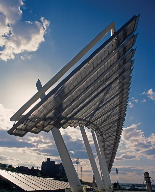 Modern solar panel canopy with steel supports against blue sky, showcasing renewable, sustainable urban design.